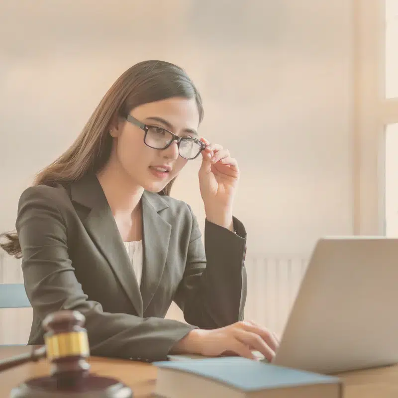 Legal Services for Friendswood TX shows woman touching her glasses and looking at a computer next to a judge's gavel.